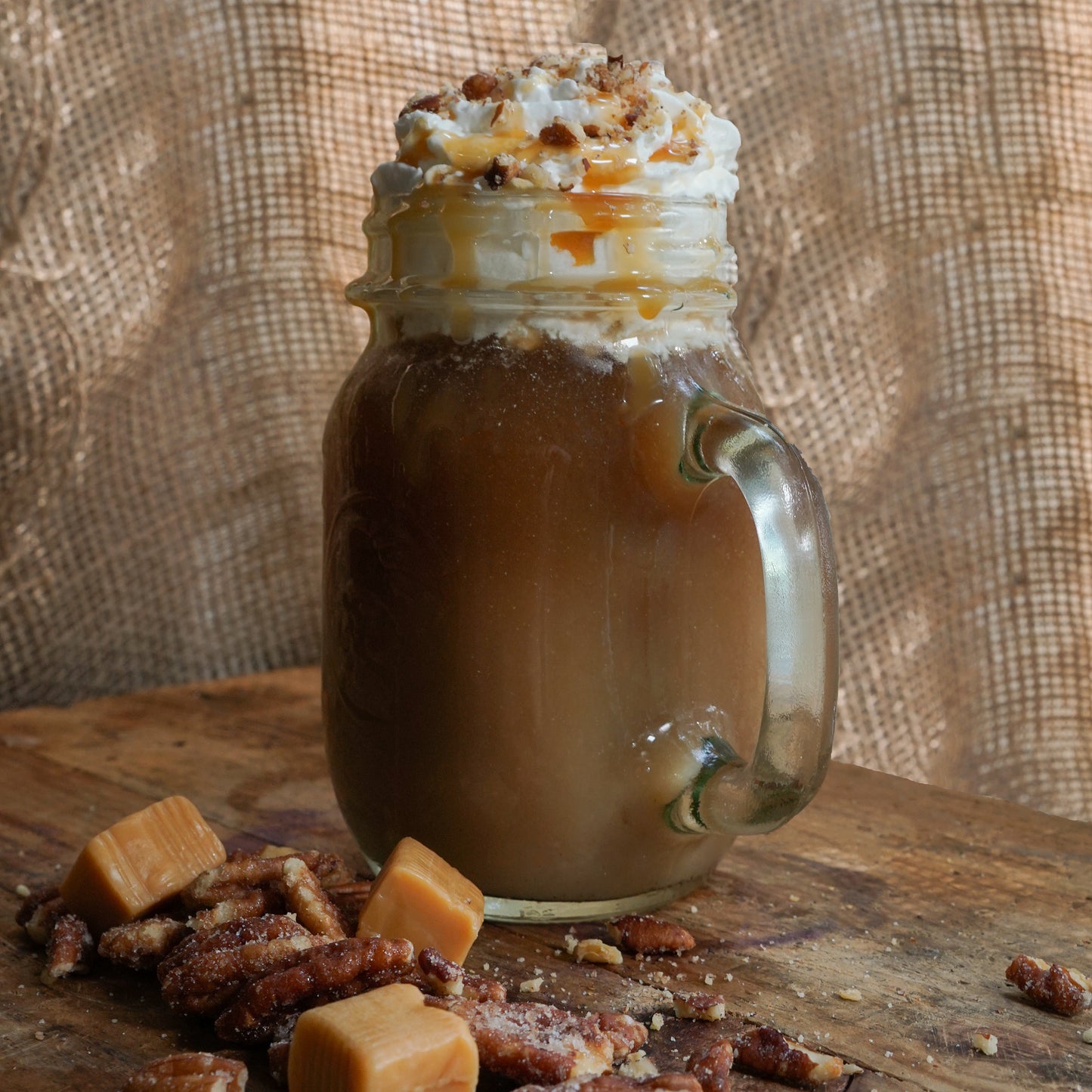Caramel pecan flavored coffee in a mug with roasted pecans and caramel drizzle
