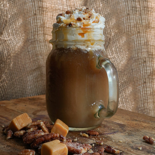 Caramel pecan flavored coffee in a mug with roasted pecans and caramel drizzle